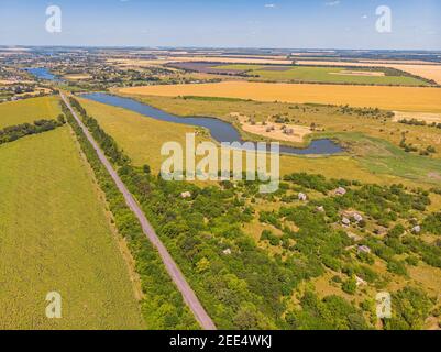 Veduta aerea di una stretta strada di campagna asfaltata grigia, che attraversa un paesaggio con campi e prati. Foto Stock