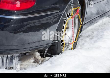 catene da neve sul pneumatico posteriore della vettura nera Foto Stock