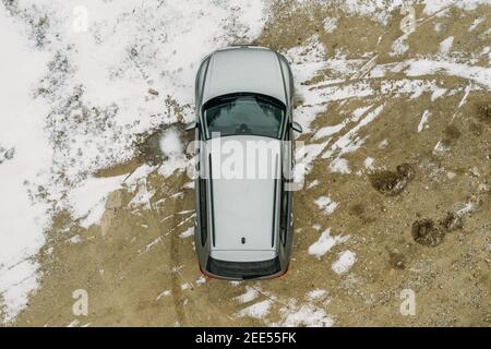 Vista aerea dall'alto della moderna SUV fuori strada su un terreno coperto di neve, concetto di avventura di viaggio invernale. Foto Stock