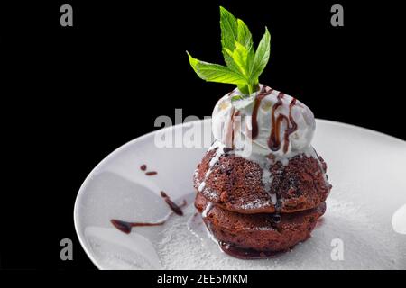 Fondente di cioccolato con gelato, su un piatto bianco, con menta e bacche Foto Stock