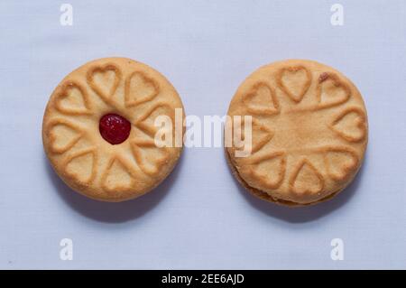 Biscotti rossi con confettura centrata con un sapore di fragola su un sfondo bianco chiaro Foto Stock