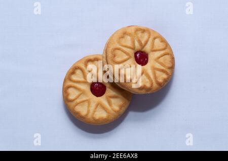 Biscotti rossi con confettura centrata con un sapore di fragola su un sfondo bianco chiaro Foto Stock