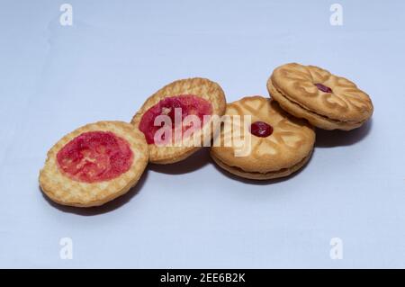 Biscotti rossi con confettura centrata con un sapore di fragola su un sfondo bianco chiaro Foto Stock