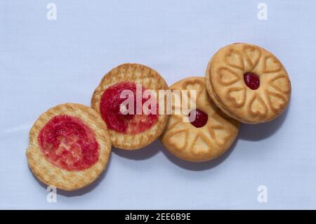 Biscotti rossi con confettura centrata con un sapore di fragola su un sfondo bianco chiaro Foto Stock