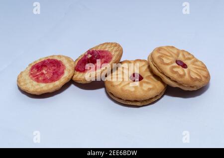 Biscotti rossi con confettura centrata con un sapore di fragola su un sfondo bianco chiaro Foto Stock