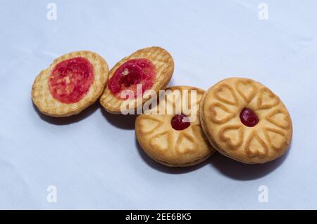 Biscotti rossi con confettura centrata con un sapore di fragola su un sfondo bianco chiaro Foto Stock