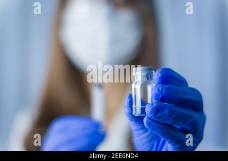 Medico femminile con stetoscopio su siringa con supporto per spalla e vaccino COVID-19. Concetto sanitario e medico. Foto Stock