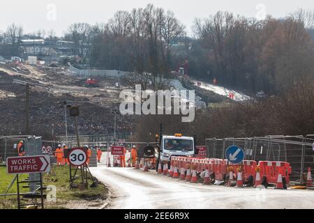 Harefield, Regno Unito. 13 febbraio 2021. Una chiusura stradale su Harvil Road nella valle del Colne è mantenuta dalle guardie di sicurezza che agiscono per conto di HS2 Ltd per facilitare l'abbattimento (dietro) di alcuni dei pochi alberi rimasti nella zona per il collegamento ferroviario ad alta velocità HS2. Quattro attivisti anti-HS2 erano stati sfrattati da un campo stradale e tre da alberi vicini da bailiffs che agiscono per HS2 Ltd durante la notte. Credit: Mark Kerrison/Alamy Live News Foto Stock