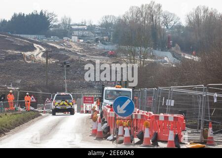 Harefield, Regno Unito. 13 febbraio 2021. Un veicolo di sicurezza si avvicina ad una chiusura stradale su Harvil Road nella valle del Colne, allestita per facilitare l'abbattimento (dietro) di alcuni dei pochi alberi rimasti nell'area per il collegamento ferroviario ad alta velocità HS2. Quattro attivisti anti-HS2 erano stati sfrattati da un campo stradale e tre da alberi vicini da bailiffs che agiscono per HS2 Ltd durante la notte. Credit: Mark Kerrison/Alamy Live News Foto Stock