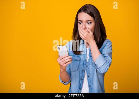 OH no. Foto di attraente giovane signora tenere braccio telefono sulla bocca leggere blog commenti negativi infelici terrorizzati occhi indossare casual denim camicia Foto Stock