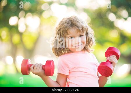 Allenamento per bambini. Bambini che si allenano con i manubri. Bambino sportivo con manubri all'aperto. Sport per bambini. Allenamento dei ragazzi nel parco. I bambini hanno uno stile di vita sano e attivo. Foto Stock