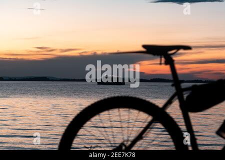 La silhouette della bicicletta e una nave al tramonto a Porto Alegre, Brasile Foto Stock