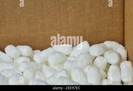 Imballaggio bianco arachidi styrofoam materiale di imballaggio popcorn all'interno di una scatola di cartone, vista angolare con spazio di copia. Foto Stock