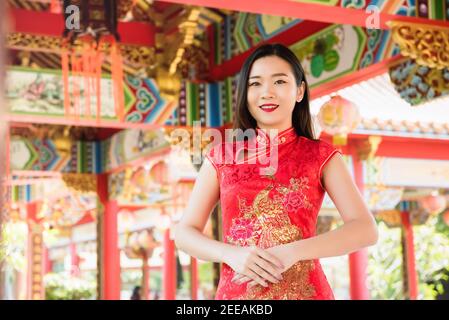 Sorridente bella donna asiatica in tradizionale cheongsam rosso vestito qipao Al tempio cinese Foto Stock