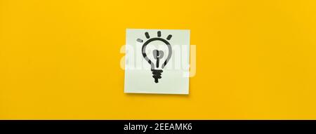 Icona a forma di lampadina disegnata a mano su carta adesiva che rappresenta idee, creatività e innovazione in colorato sfondo giallo banner Foto Stock