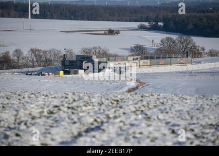 Dannenrod, Germania. 14 Feb 2021. Protetto da contenitori, recinzioni, telecamere di sorveglianza e contenitori e pareti di terra è il deposito macchine delle imprese edili, ai margini della zona di schiarimento per l'autostrada 49. (Per 'la consegna delle aree liquidate alla società di costruzioni è imminente') credito: Boris Roessler/dpa/Alamy Live News Foto Stock