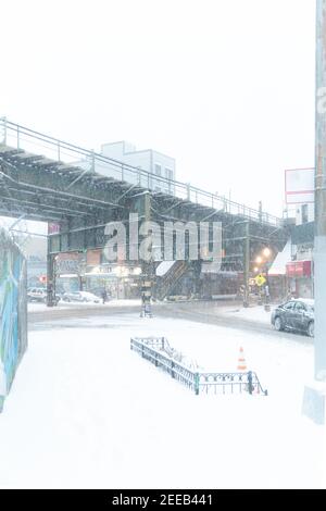 Una strada cittadina con un treno sopraelevato è in quasi condizioni di whiteout. La neve sta cadendo così velocemente che la strada della città è quasi completamente invisibile. Foto Stock