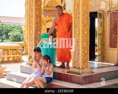 Monaco che ha eseguito una benedizione dell'acqua su un uomo e una ragazza a Wat Kean Kliang, un tempio buddista a Phnom Penh, Cambogia, situato tra il Tonle SAP e. Foto Stock