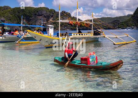 El Nido, le Filippine - 20 Nov 2018: Paesaggio marino con barca turistica e venditore di cibo in kayak. Vendita di cibo di strada sulla spiaggia. Palawan giro in barca scena Foto Stock