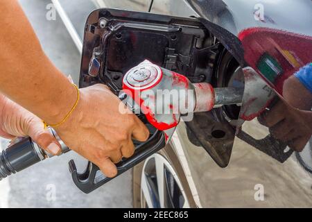 Uomini tenere ugello carburante per aggiungere carburante in auto a. stazione di servizio Foto Stock