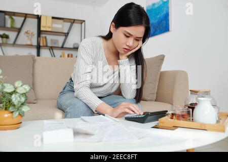 Donna stressata che calcola le spese Foto Stock