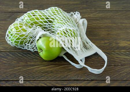 Mele Granny Smith biologiche in sacchetto di tessuto a maglia su legno tabella Foto Stock