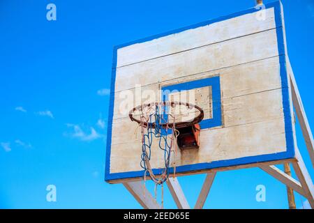 Basketball backboard su sfondo blu cielo. Attrezzature sportive all'aperto rustiche. Concetto di attività all'aperto in estate. Pallacanestro che gioca all'esterno. Vecchio cestino o Foto Stock
