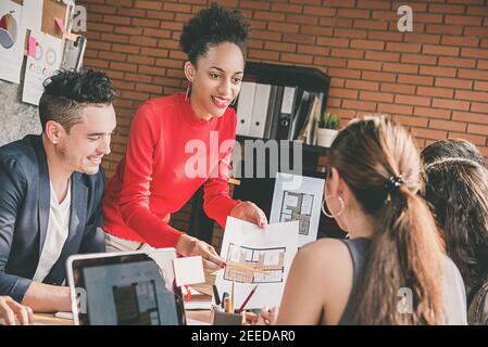 Architetto o designer d'interni uomo d'affari che condividono progetto di pianta idee con i suoi colleghi multietnici in ufficio Foto Stock