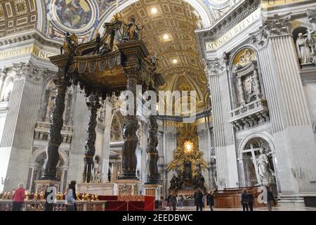 Turisti che ammirano l'altare Pontificio e Baldacchino di Bernini (1633) nella Basilica di San Pietro, in Vaticano. Foto Stock