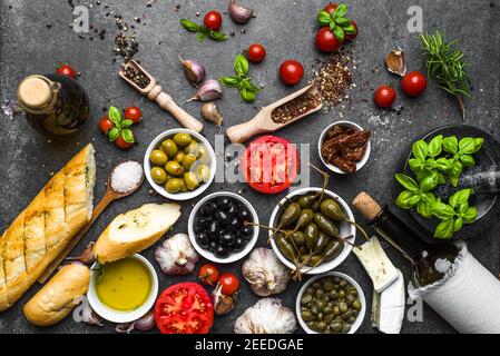 Cibo mediterraneo di fondo. Cottura degli ingredienti su pietra scura. Foto Stock