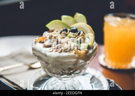 Bella e appetitosa insalata di frutta allo yogurt con cereali di avena per colazione Foto Stock