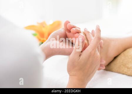 Un cliente che riceve un massaggio thailandese del piede con riflessologia e aromaterapia. Foto Stock