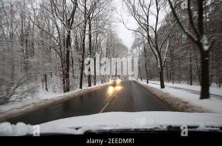 Berlino, Germania. 16 Feb 2021. Un'auto attraversa una strada innevata. La neve fresca dell'ultima notte e le strade vetrose stanno causando ostruzioni nel traffico delle ore di punta del mattino a temperature intorno a meno un grado Celsius. Secondo i meteorologi, la neve cambierà in pioggia nei prossimi giorni e le temperature nella gamma a due cifre più sono previste. Credit: Wolfgang Kumm/dpa/Alamy Live News Foto Stock