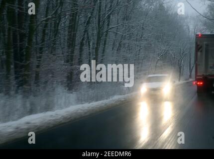 Berlino, Germania. 16 Feb 2021. Un'auto si muove su una strada innevata. La neve fresca dell'ultima notte e le strade a specchio stanno causando ostacoli nel traffico delle ore di punta del mattino a temperature intorno a meno un grado Celsius. Secondo i meteorologi, la neve cambierà in pioggia nei prossimi giorni e le temperature nella gamma a due cifre più sono previste. Credit: Wolfgang Kumm/dpa/Alamy Live News Foto Stock