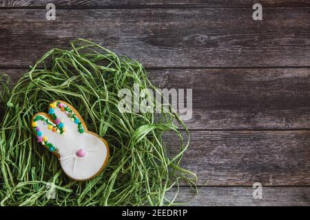 Pasqua biscotti fatti a mano coniglietto in nido su sfondo di legno. Disposizione piatta, vista dall'alto Foto Stock