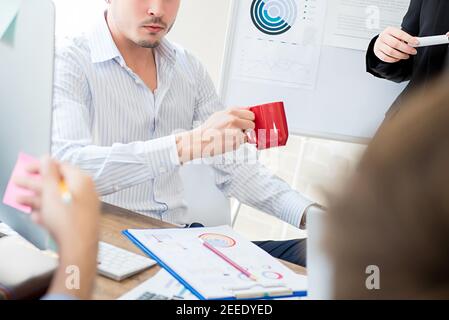 Uomo d'affari che prende una pausa bevendo caffè dopo l'incontro con i colleghi in ufficio Foto Stock