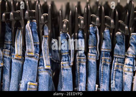 Jeans blu appesi nel negozio di moda. Cravatta Dye jeans vestiti foto. Abbigliamento unisex su appendiabiti in negozio. Vendita Fashion Shop Black Friday. I vestiti alla moda partono Foto Stock