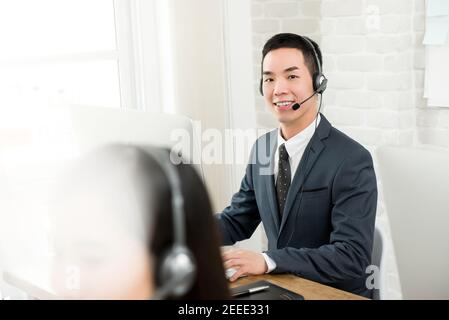 Sorridente uomo asiatico telemarketing servizio clienti agente di lavoro in chiamata centro Foto Stock