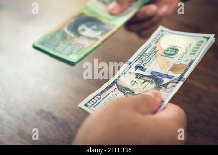 Mano che tiene le fatture del dollaro degli Stati Uniti che commercia con i dollari Australain - concetto di conversione e scambio di denaro Foto Stock