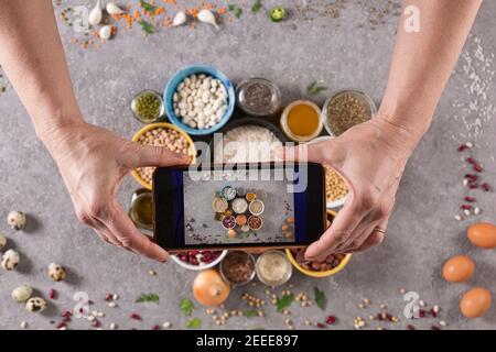 Donna che scatta foto di alimenti dietetici con smartphone Foto Stock