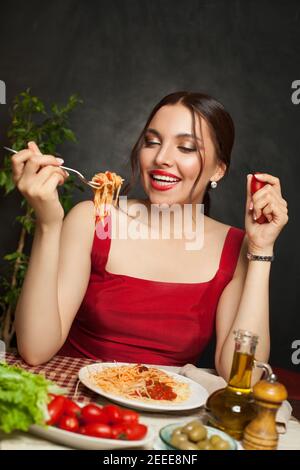 Giovane donna che mangia pasta e sorride al ristorante Foto Stock