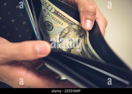 Un uomo che apre il portafoglio alla ricerca di alcuni soldi Foto Stock