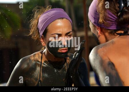 Ragazza giovane nero facendo terapia del fango del Mar Morto, Giordania Foto Stock