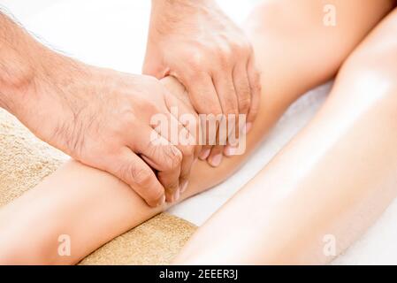 Mani di terapeuta maschile (massaggiatore) che offrono un rilassante massaggio tailandese alle gambe trattamento a una donna in spa Foto Stock