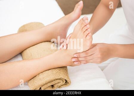 Terapista professionista che offre un rilassante massaggio tradizionale tailandese riflessologia plantare una donna in spa Foto Stock