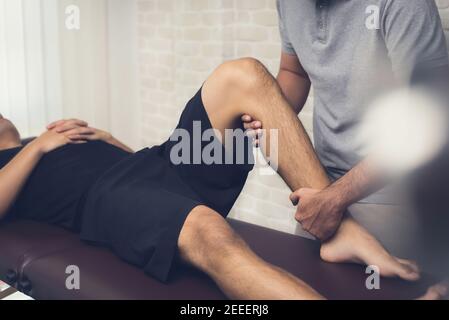 Terapeuta maschile che dà massaggio alle gambe al paziente atleta - sport concetto di terapia fisica Foto Stock