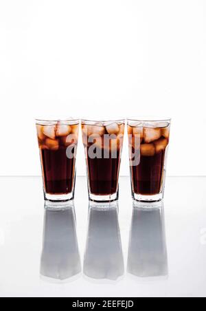 tre bicchieri di cola e ghiaccio su sfondo bianco. bevande analcoliche e. Foto Stock