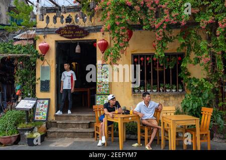 Hoi An, Vietnam - 26 lug 2019: Ristorante nella città storica. Casa gialla con lanterna cinese rossa. Turista asiatico in un caffè d'epoca. Ristorante vietnamita Foto Stock