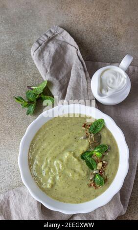 Zuppa vegetariana di verdure verdi (broccoli, piselli verdi, spinaci) servita con menta e semi su fondo di cemento. Mangiare pulito, foo sano Foto Stock