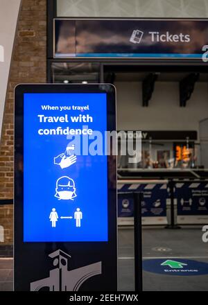 Kings Cross Hands Face Space Mask che indossa il segnale dello schermo di guida Presso la biglietteria della stazione ferroviaria durante le limitazioni di viaggio pandemiche di Coronavirus Londra Foto Stock